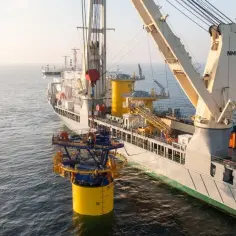 Okręt z potężnym dźwigiem przygotowuje się do instalacji elementu morskiej farmy wiatrowej, symbolizując **bałtycką moc** i przyszłość energetyczną.