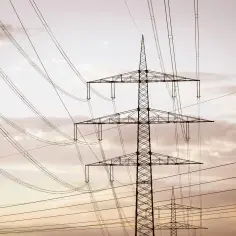 Wysoki słup na działce, który stoi tam od ponad 30 lat, otoczony siecią przewodów elektrycznych na tle zachmurzonego nieba.