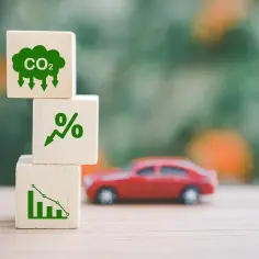 Trzy kostki z symbolami: chmura CO2, procent ze strzałką w górę, wykres słupkowy ze spadkiem. W tle czerwony samochód. Może to symbolizować ets2 podatek.