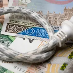 Kabel z wtyczką leży na polskich banknotach. Rosnące ceny energii to spory dodatek do prądu.
