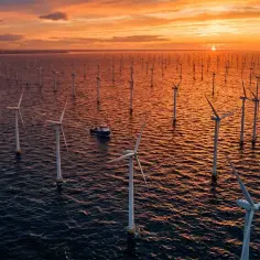 Wielka farma wiatrowa na morzu o zachodzie słońca. Wiele turbin wiatrowych, które są przyszłościowymi źródłami energii, stoi w wodzie.