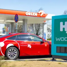 Czerwony samochód wodorowy przy stacji Orlen. Rozwijają się stacje wodorowe w Polsce, oferując ekologiczne paliwo.