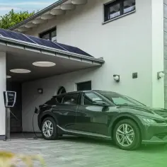 Nowoczesny dom z panelami słonecznymi i ładowarką do samochodu elektrycznego, który pobiera czyste jednostki energii.