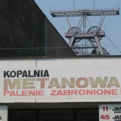 Kopalnia metanowa, gdzie wybuch metanu jest realnym zagrożeniem. Widoczna wieża szybu kopalnianego i tablica "PALENIE ZABRONIONE!".