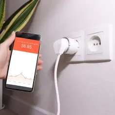 Smart wtyczka monitoruje zużycie prądu. Na telefonie widać wykres, który pokazuje średnie zużycie prądu dla 2 osób.
