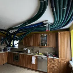 W kuchni starego domu instalacja rekuperacji z zielonymi i niebieskimi przewodami oplata sufit.