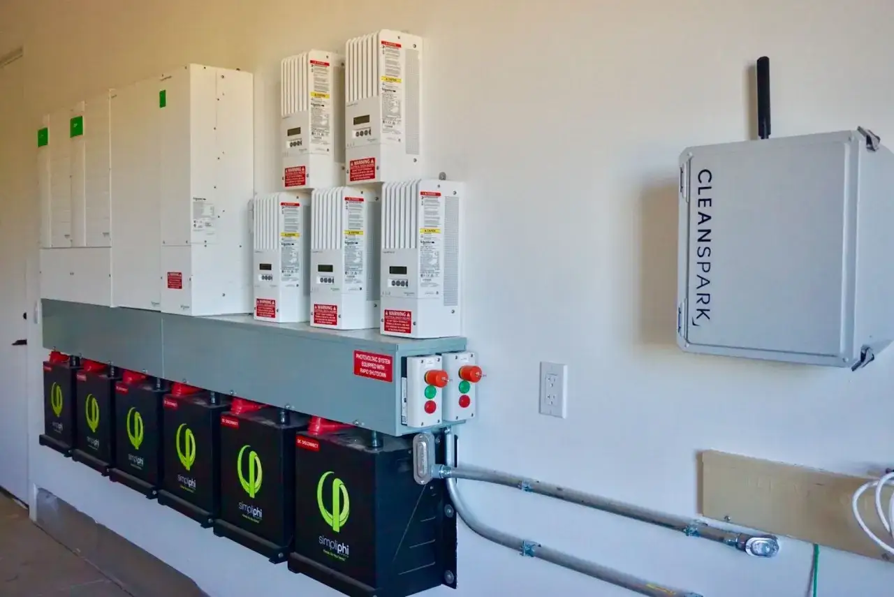 System magazynowania energii z bateriami Simpliphi i falownikami Schneider. Na ścianie obok urządzeń CleanSpark.