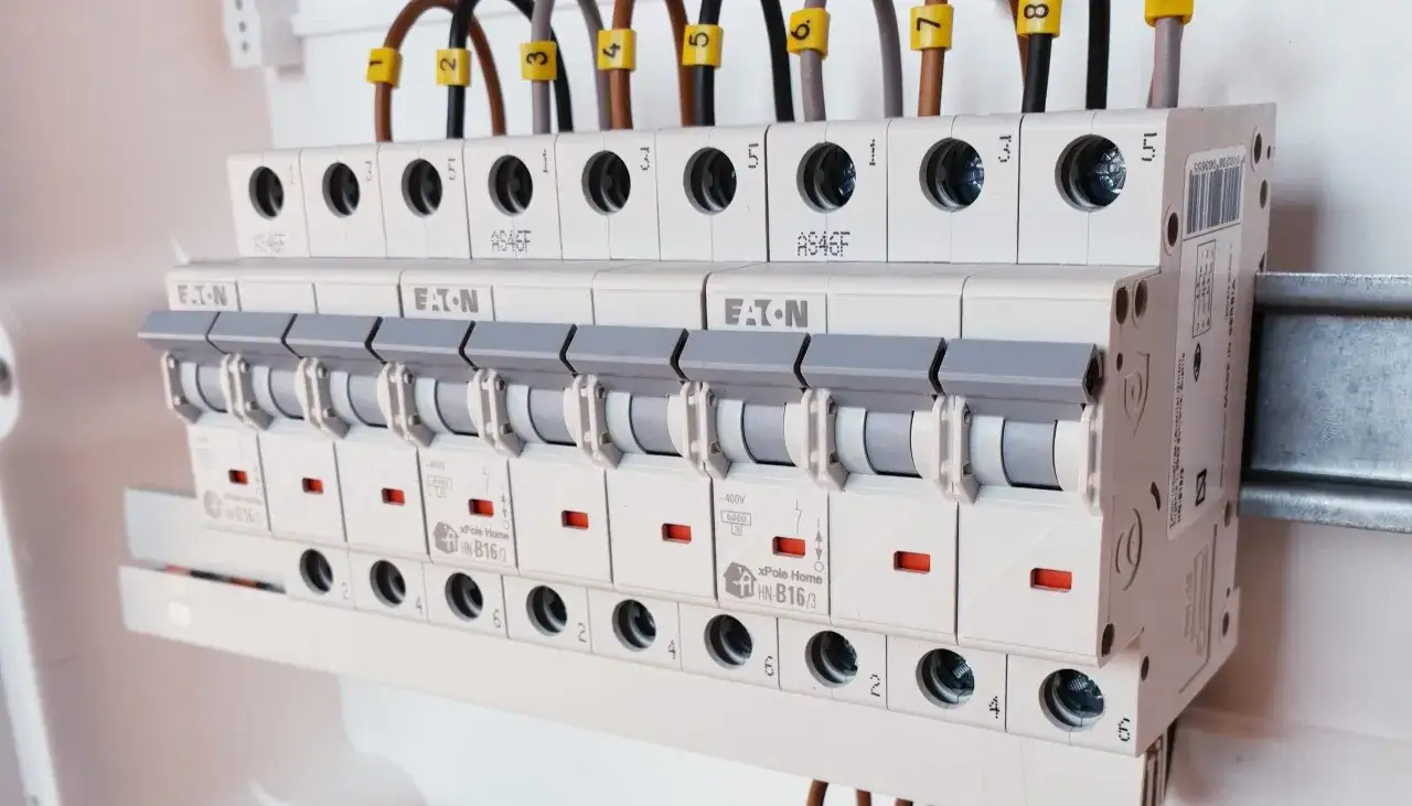 Szereg bezpieczników automatycznych, każdy z dźwignią i oznaczeniem, stanowi zabezpieczenie instalacji. To jest ogranicznik mocy.