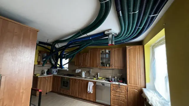 W kuchni starego domu instalacja rekuperacji z zielonymi i niebieskimi przewodami oplata sufit.